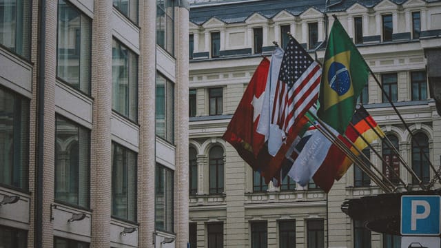 View of international flags outside an urban building in daylight, symbolizing global unity.