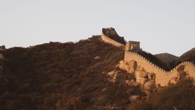 Stunning view of the Great Wall of China at sunset during autumn, highlighting historic architecture and scenic landscapes.