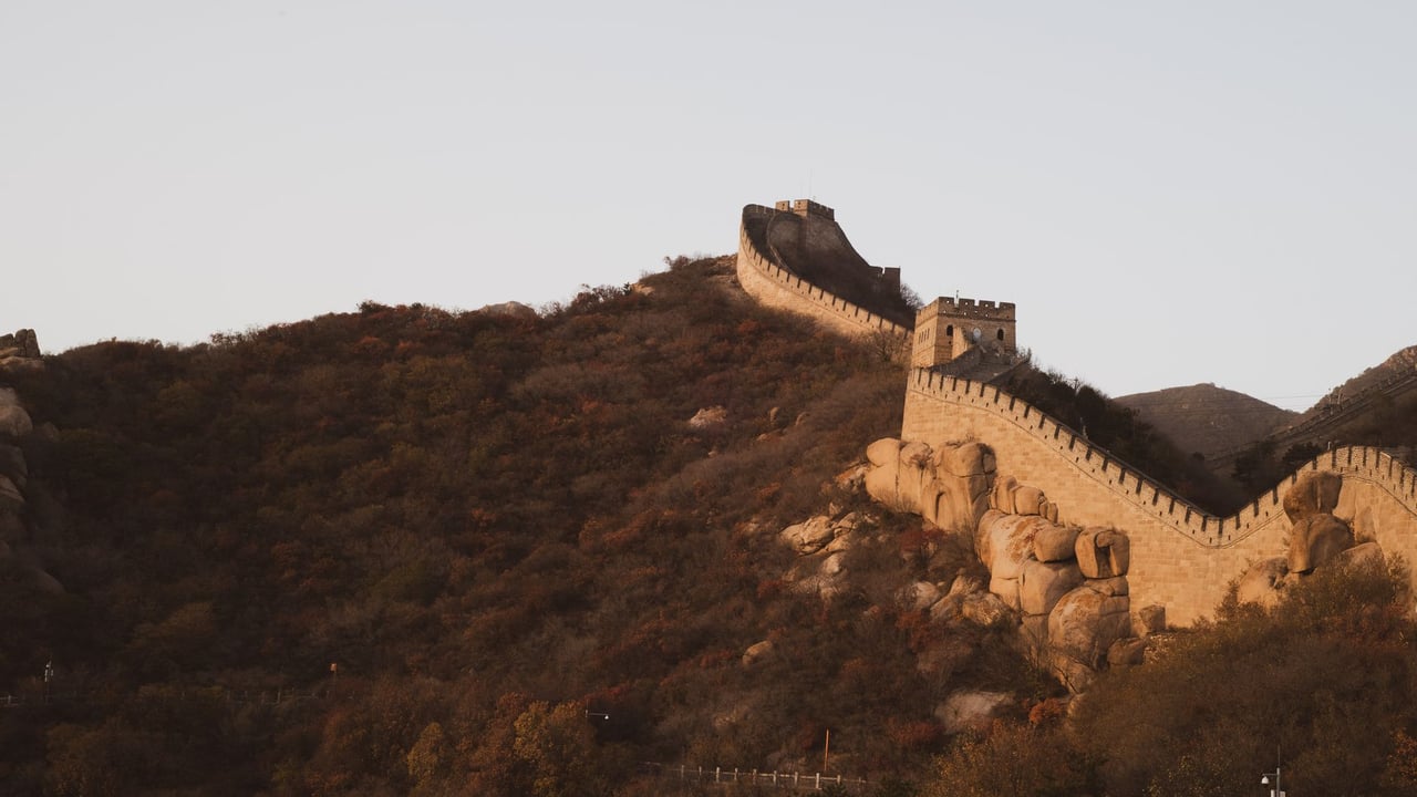 Stunning view of the Great Wall of China at sunset during autumn, highlighting historic architecture and scenic landscapes.