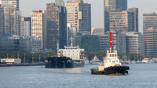 Explore the bustling waterfront of Shanghai with boats and towering modern skyscrapers.