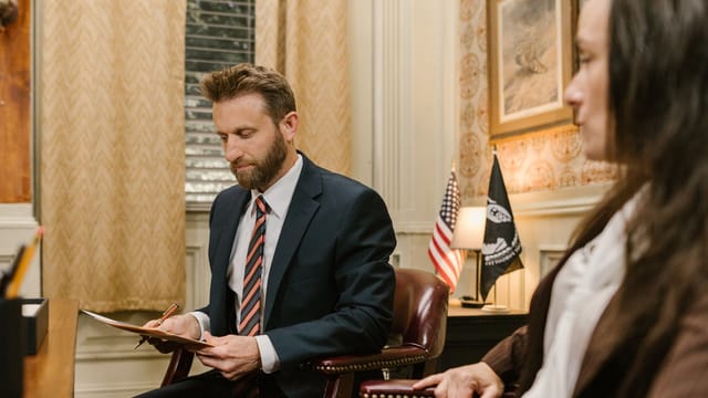A lawyer in business attire reviewing documents during a meeting in an office.