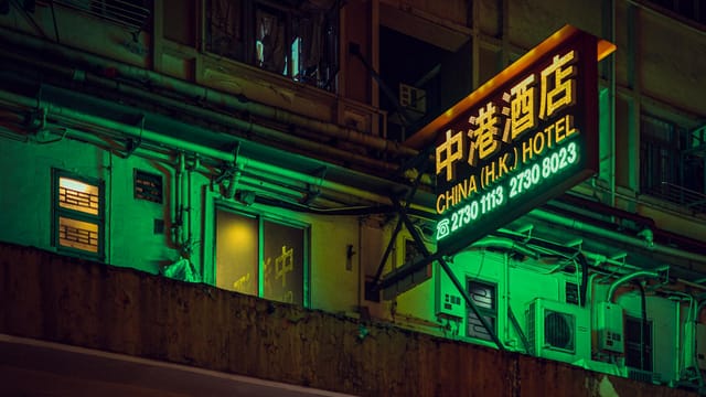 A neon-lit hotel sign illuminates the bustling streets of Hong Kong, capturing the city's vibrant nightlife.