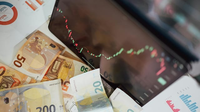 Close-up of euro banknotes with a digital stock market chart displaying a downward trend, symbolizing financial volatility.