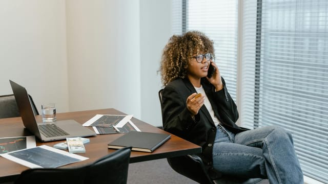 A business analyst engaged in work, sitting at a desk with a laptop and graphs.