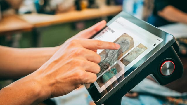 Close-up of hands interacting with a touchscreen device, showcasing digital content.