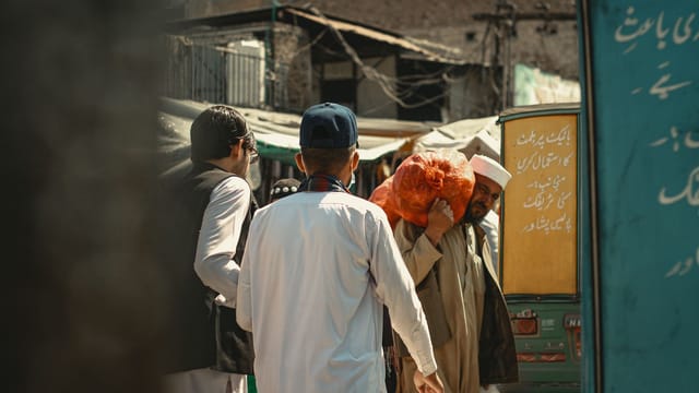 A lively street photo capturing daily life in Peshawar with local shops and people.