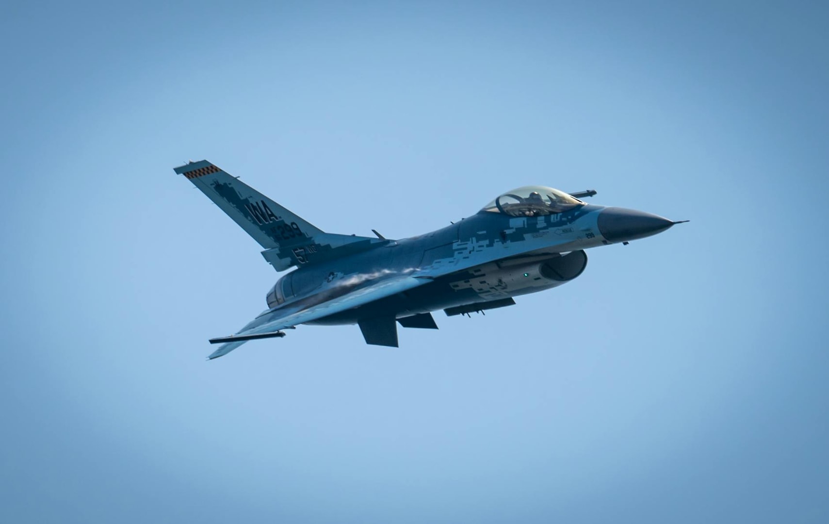 A fighter jet soaring through the clear blue sky at high speed.