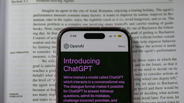 Smartphone showing OpenAI ChatGPT in focus, on top of an open book, highlighting technology and learning.