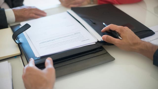 Two professionals discussing a contract with documents on a table, indoors.