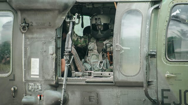 Soldier in military helicopter cockpit in Colombia, demonstrating readiness.