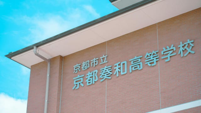 Brick building facade with Japanese text under a clear blue sky in Kyoto, Japan.