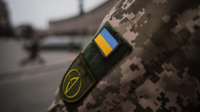 Detailed shot of Ukrainian military uniform with flag patch, symbolizing national pride.