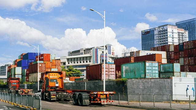 Colorful shipping containers stack at an industrial port under clear skies.