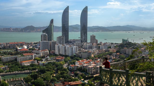 Panoramic view of Xiamen skyline with dramatic sea and skyscrapers on a clear day.
