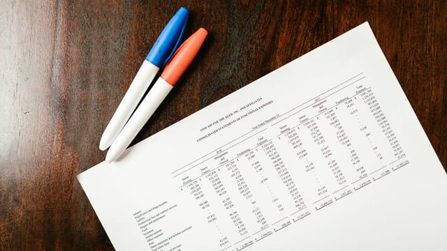 A financial statement on a wooden desk with colorful pens, ideal for accounting themes.